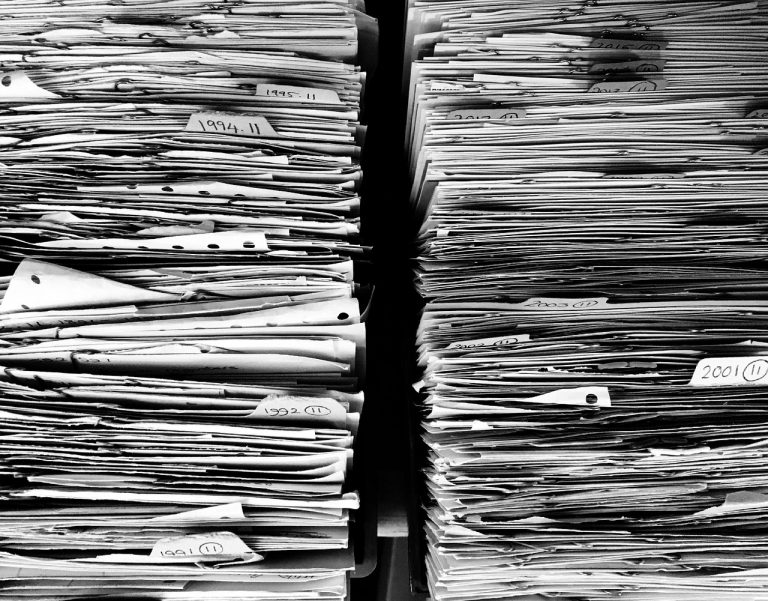 Bărbat care sortează acte într-un dosar pe un birou, cu un calendar în apropiere